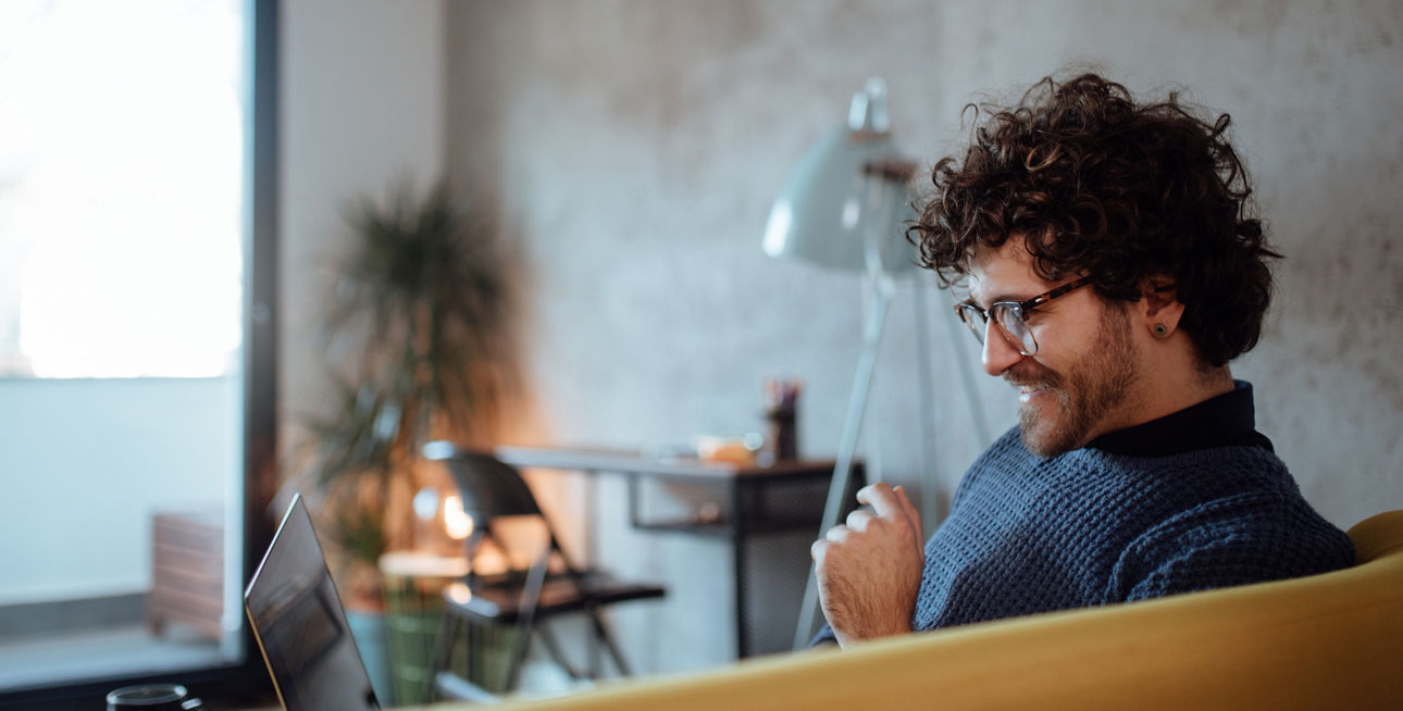 Mann sitzt auf seiner Couch am Laptop
