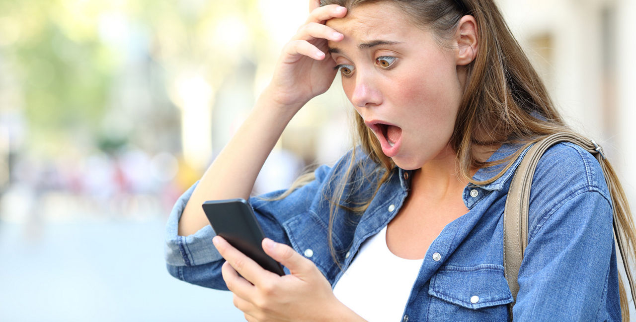 Frau schaut entsetzt auf ihr Handy