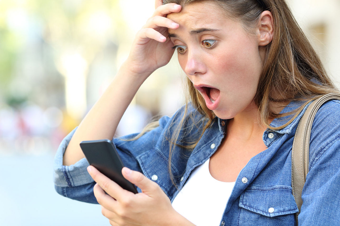 Frau schaut entsetzt auf ihr Handy