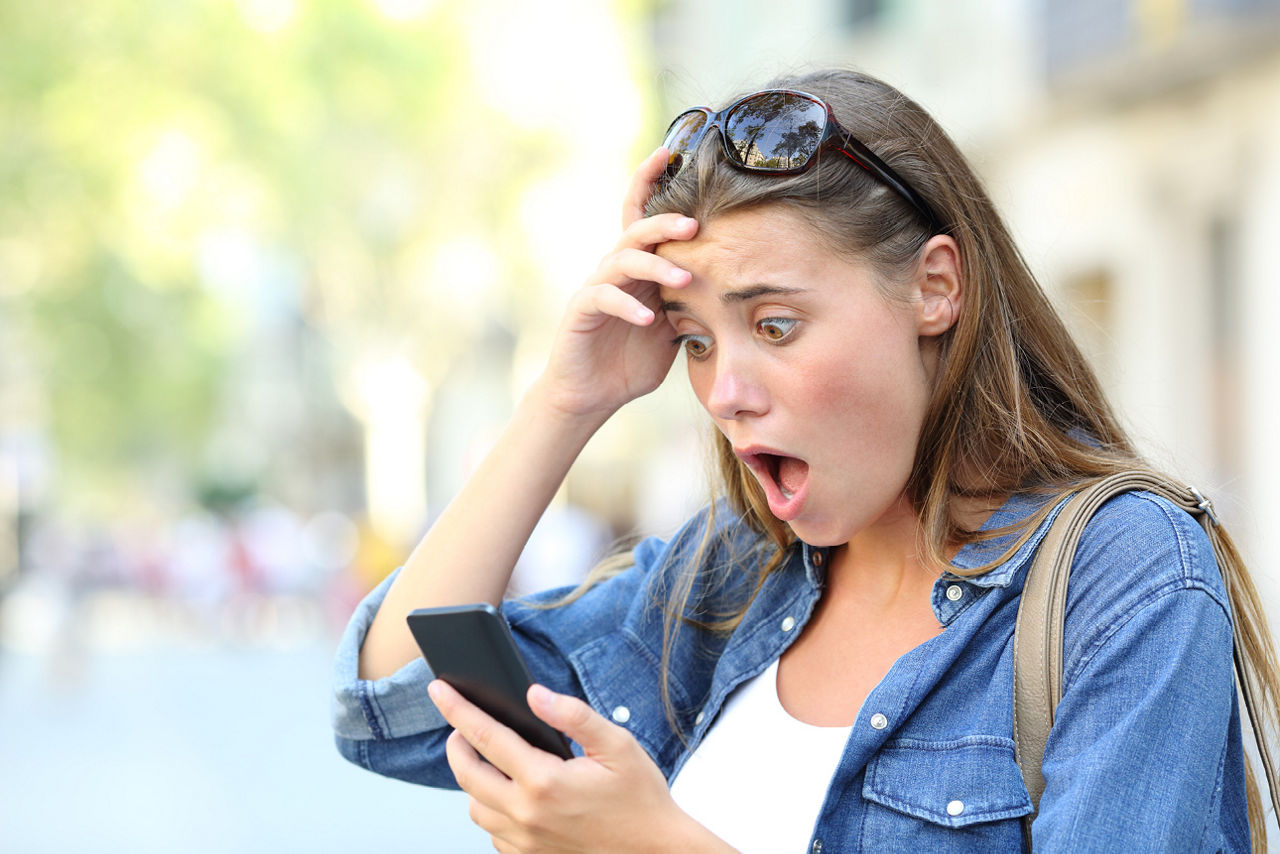 Frau schaut entsetzt auf ihr Smartpone
