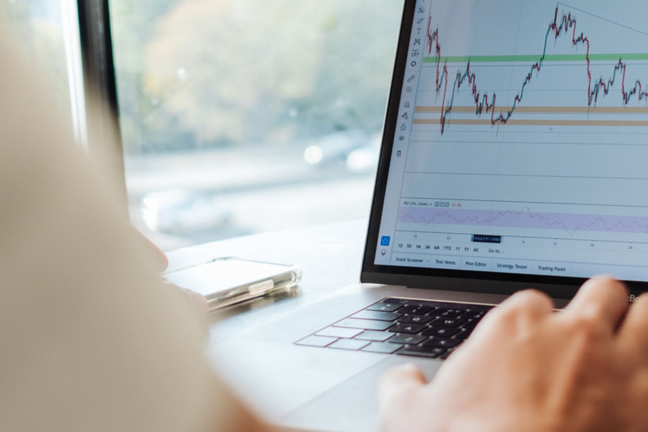 Person sichtet Kursverläufe der Börse auf dem Laptop