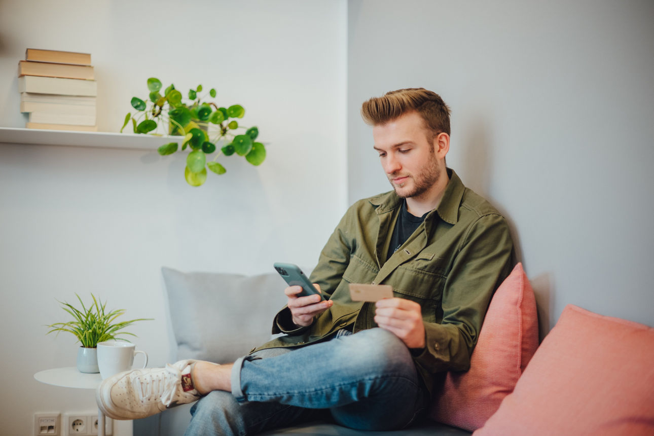 Ein Mann sitzt auf einer Couch und schaut in sein Handy