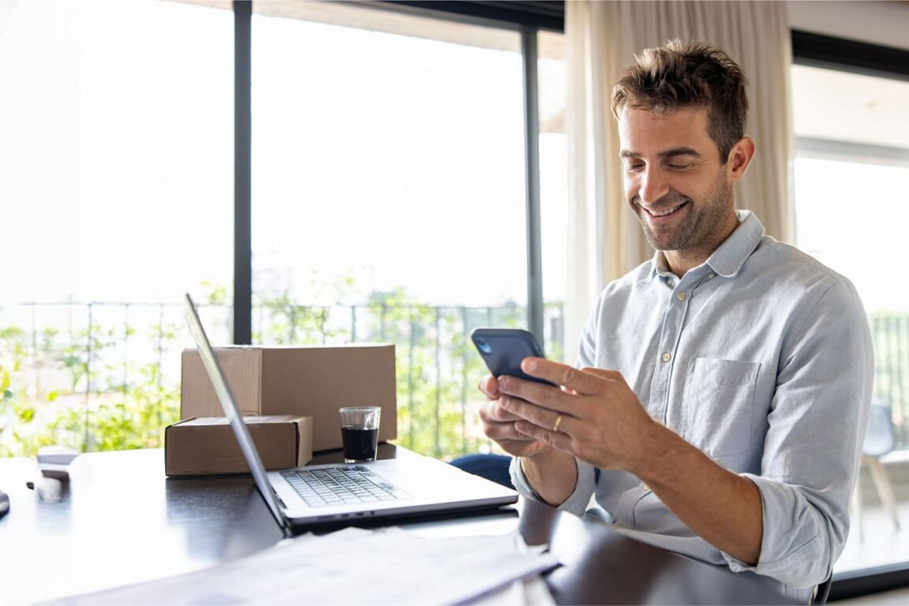 Ein Geschäftsmann schaut lächelnd auf sein Smartphone