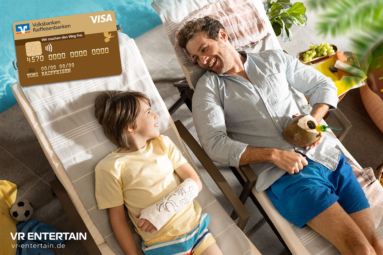 Vater und Sohn mit Arm im Gips liegen im Urlaub auf Sonnenliegen und lachen sich an