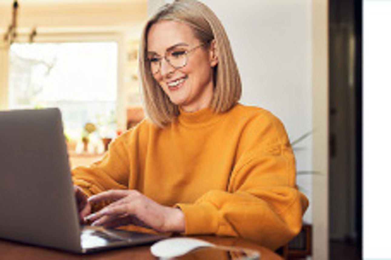 Frau in gelben Pullover vor Laptop