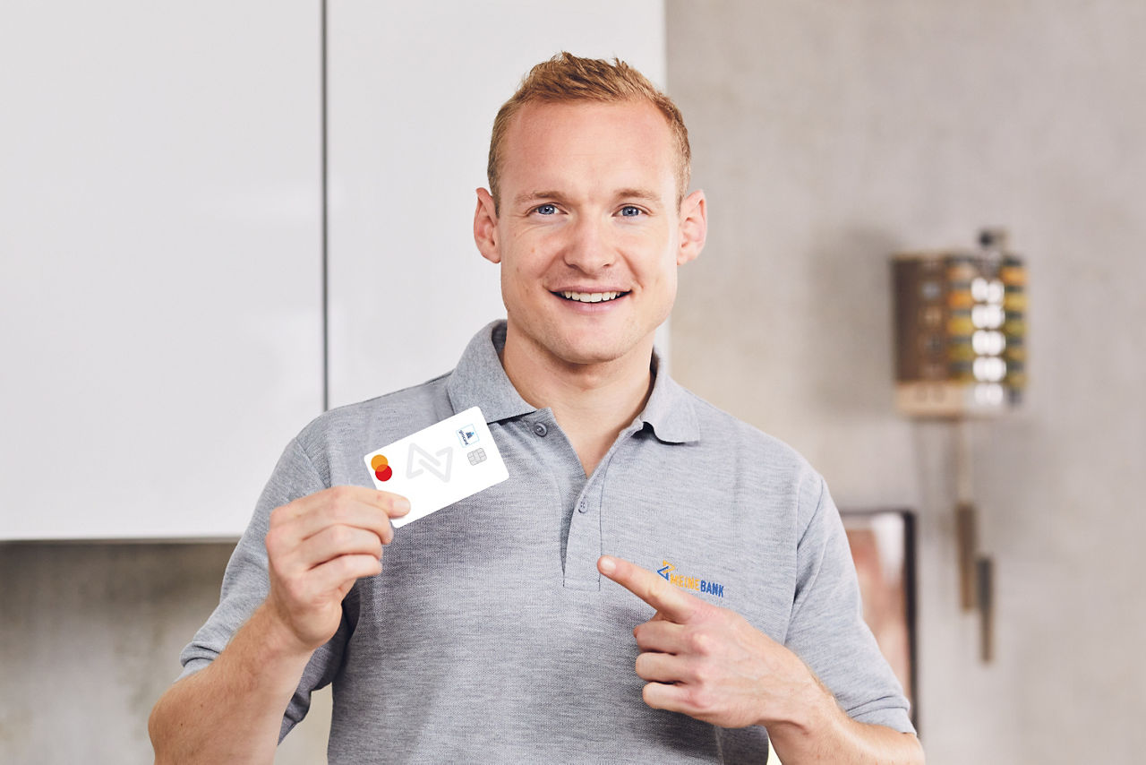 Abbildung zeigt Sebastian Rode (ehemaliger Fussballspieler und Markenbotschafter, welcher die girocard von Meine Bank hält.
