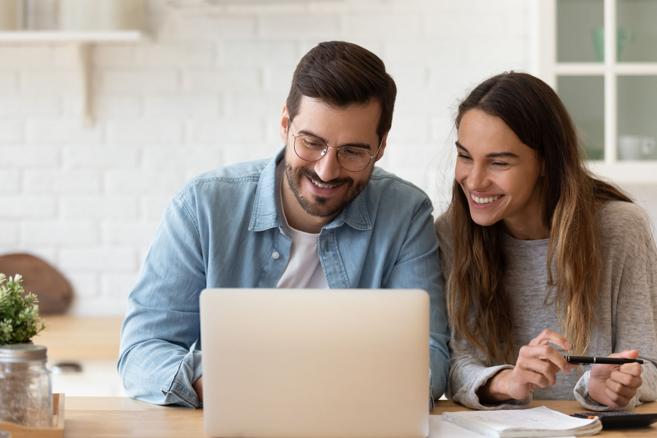 Mann und Frau schauen erfreut auf ein Laptop