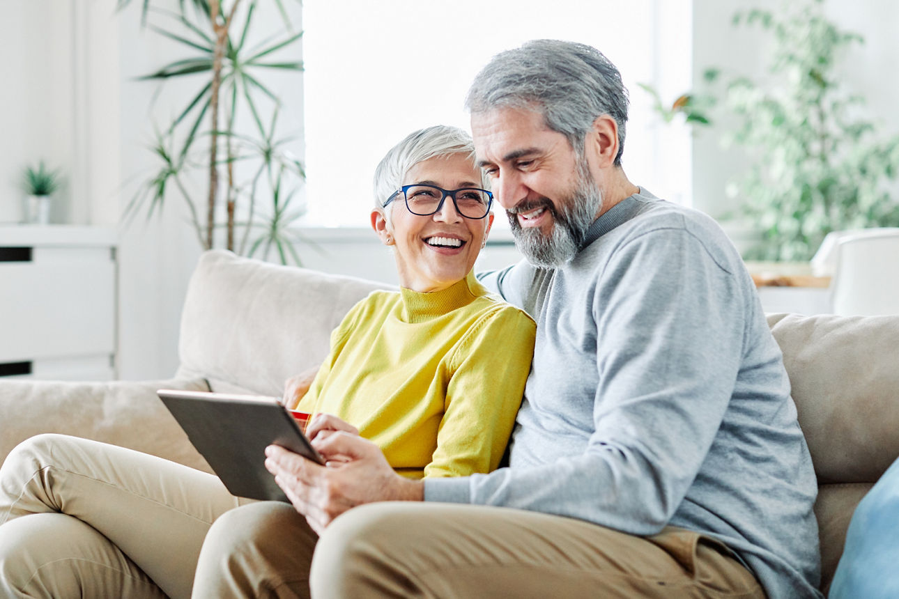Ein Paar sitzt auf einer Couch und halten ein Tablet in Händen