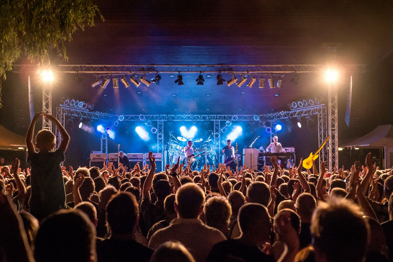 Viele Menschen schauen bei einem Konzert einer Band auf der Bühne zu