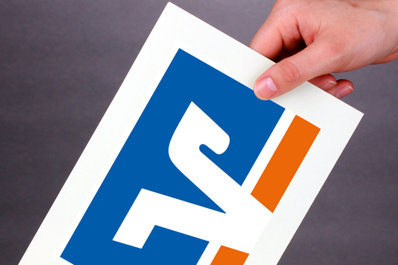 Eine Hand, die einen Stimmzettel mit Volksbank-Logo einwirft.