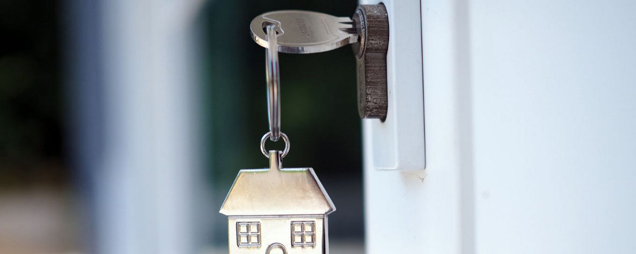 Schlüssel in Wohnungstür mit Hausanhänger