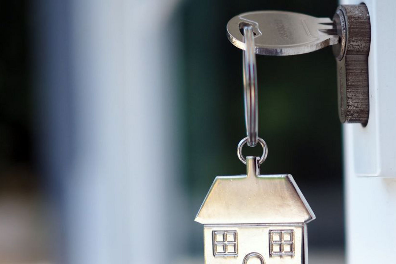 Schlüssel in Wohnungstür mit Hausanhänger