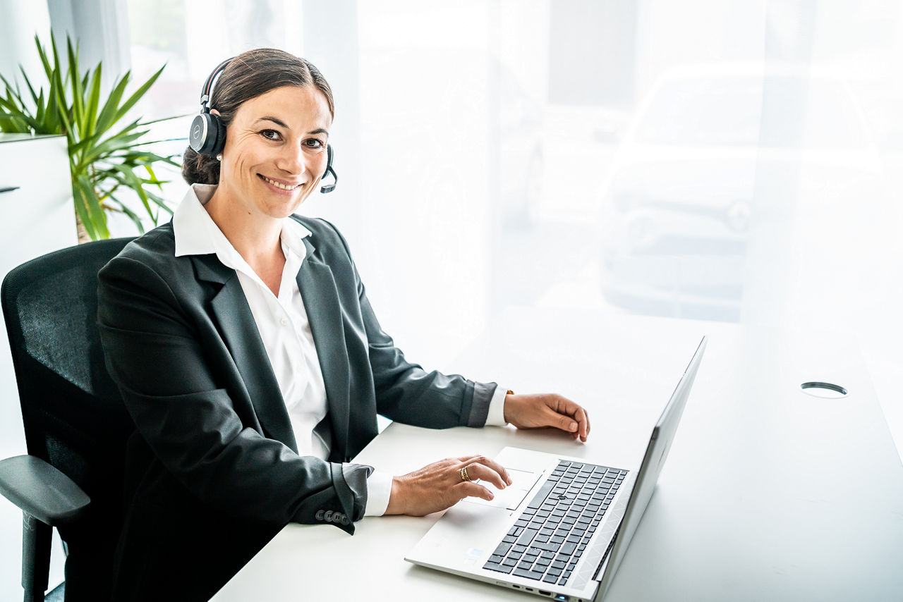 Eine Frau mit Headset lächelt in die Kamera