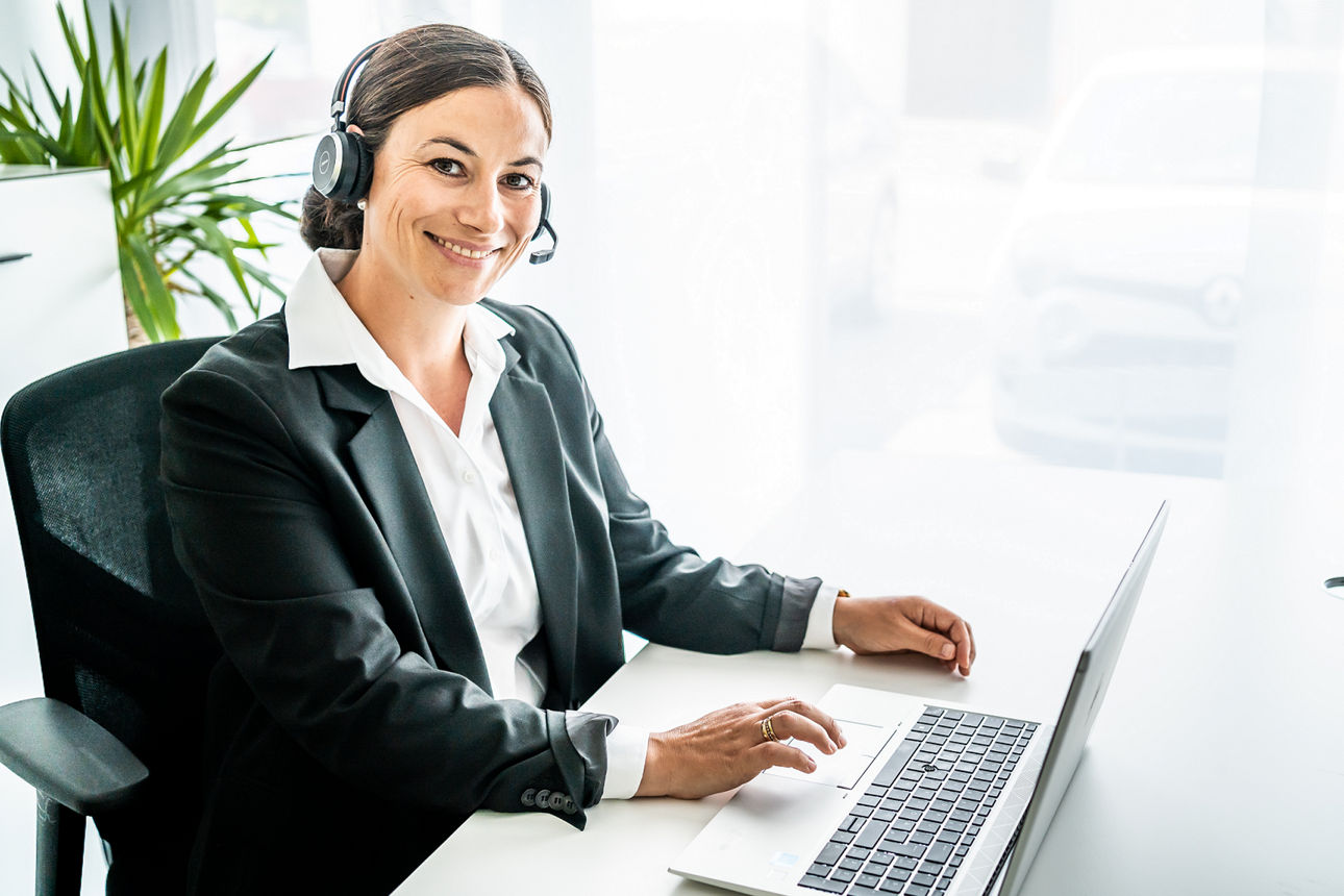 Eine Frau mit Headset lächelt in die Kamera
