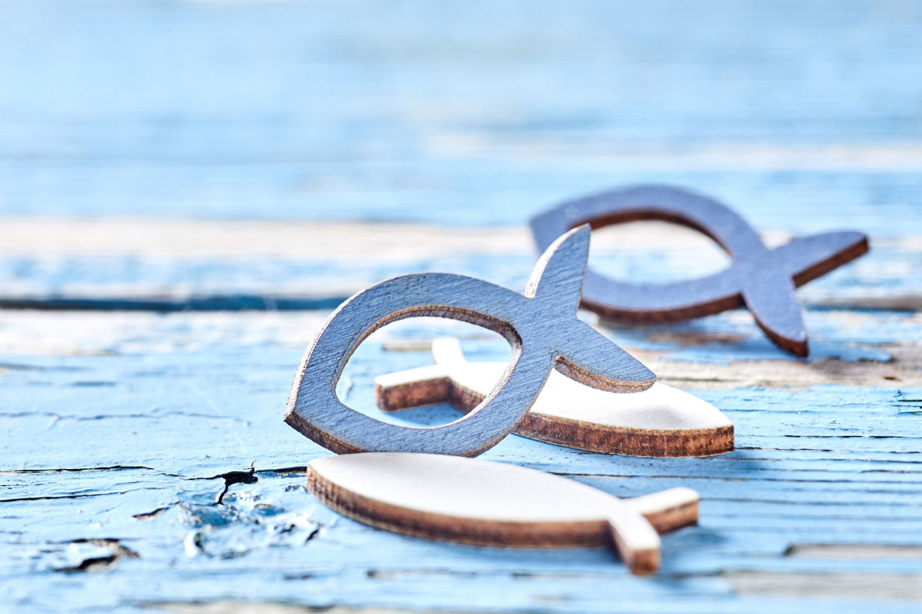 Drei Holzfische auf blauem Hintergrund