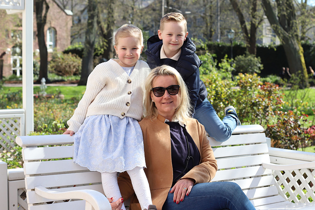 Mutter mit zwei kleinen Kindern sitzen auf einer Bank
