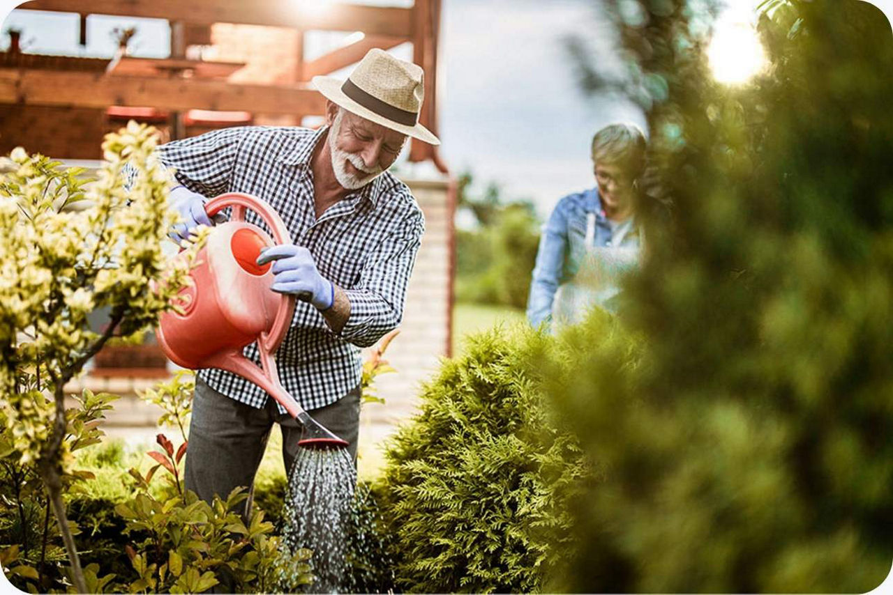 Mann gießt Blumen in seinem Garten
