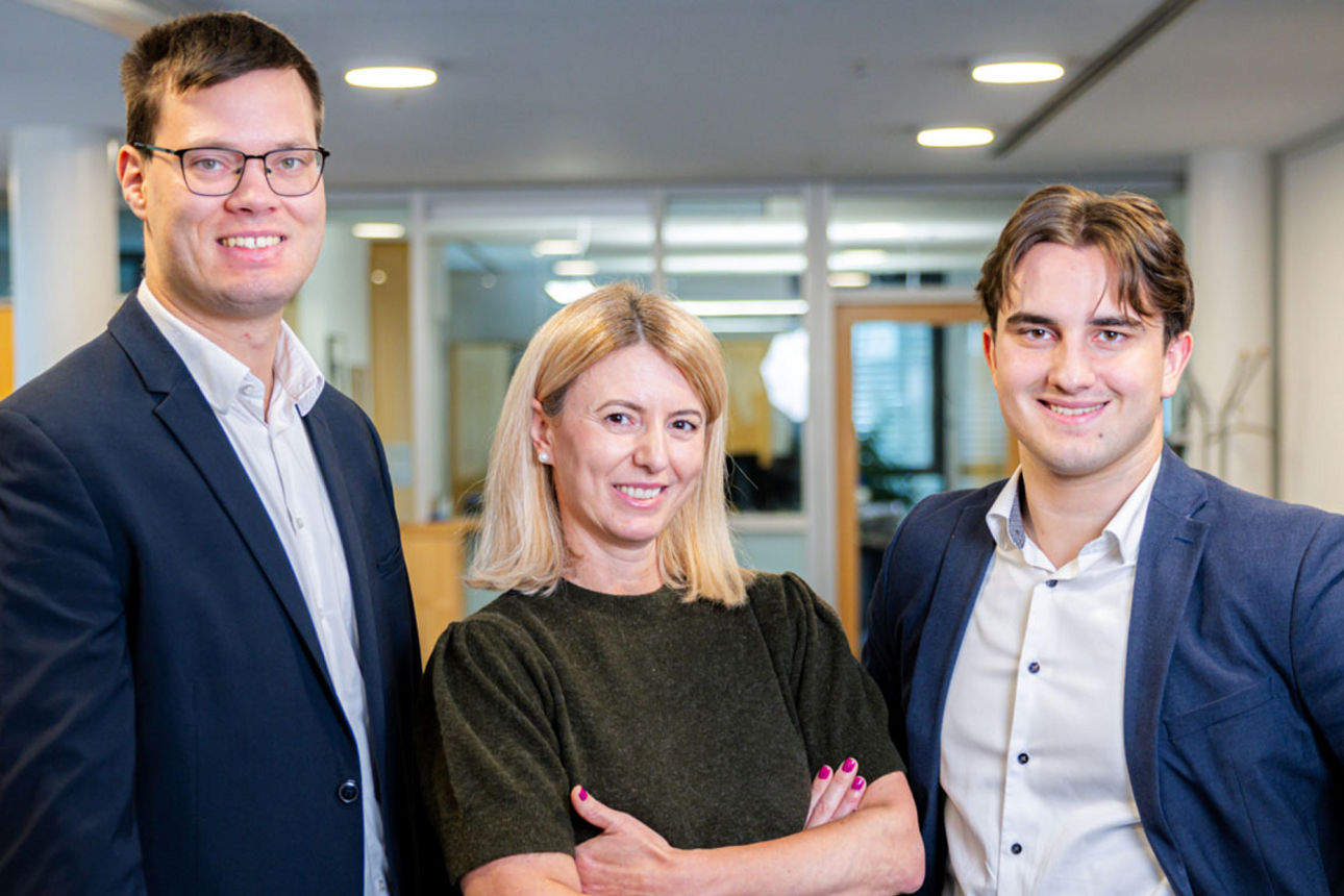 Ein junger Mann sitzt lächelnd am Schreibtisch