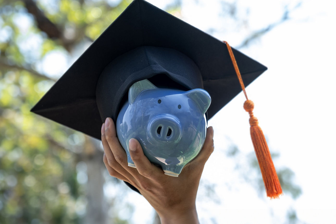 Hand holding Blue piggy bank with  graduation hat, Saving money for education plan and retirement fund concept.