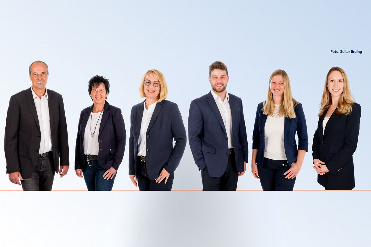 Mann und Frau im Gespräch mit Bankberaterin vor dem Rohbau einer Immobilie