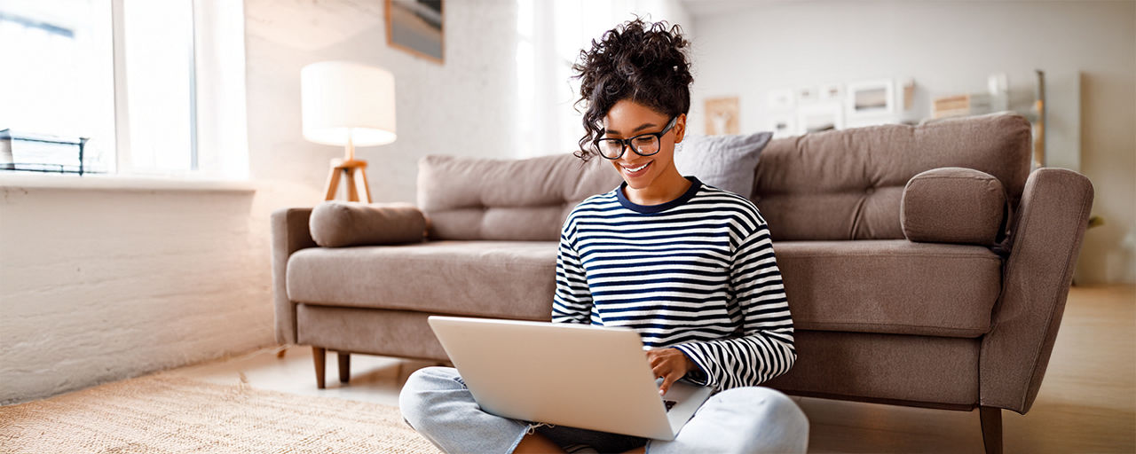 Frau auf dem Boden sitzend mit Laptop
