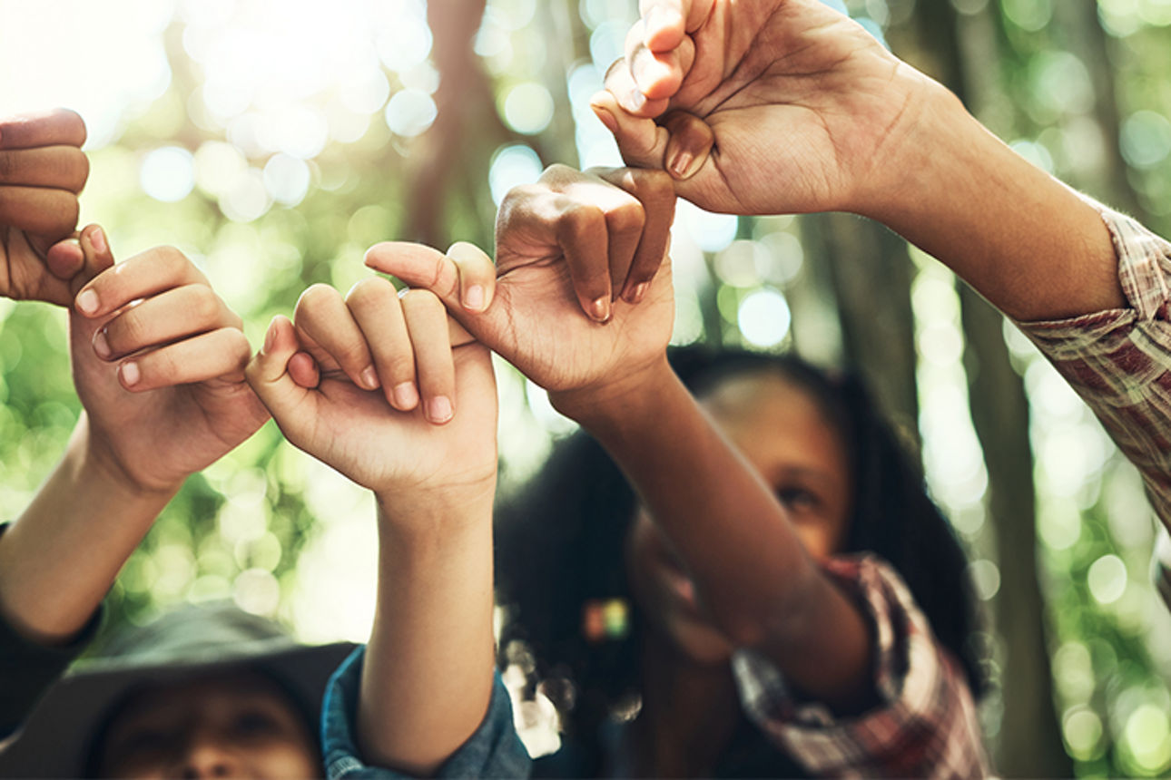 Mehrere Kinder halten ihre Hände in der Mitte zusammen und bilden einen Kreis.