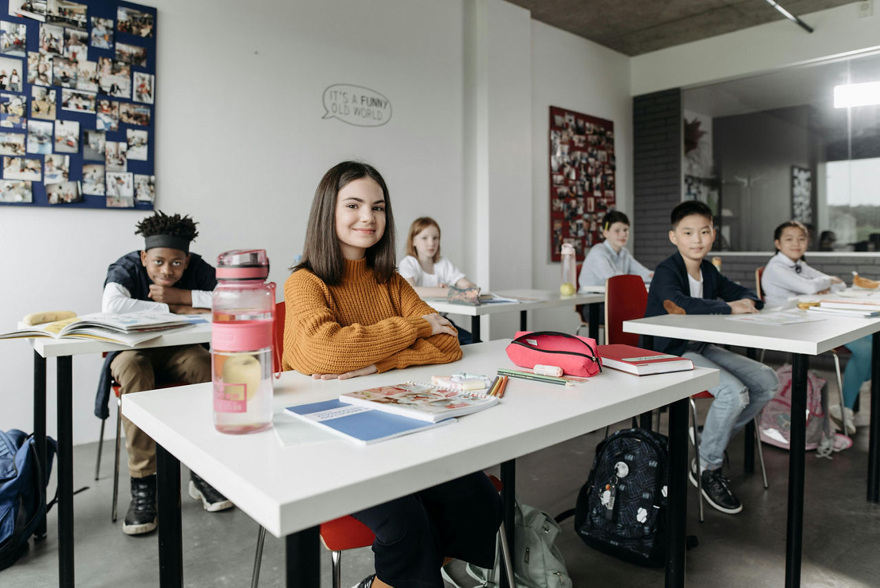 Schüler sitzen in der Klasse, im Vordergrund ist ein Mädchen am Tisch zu sehen