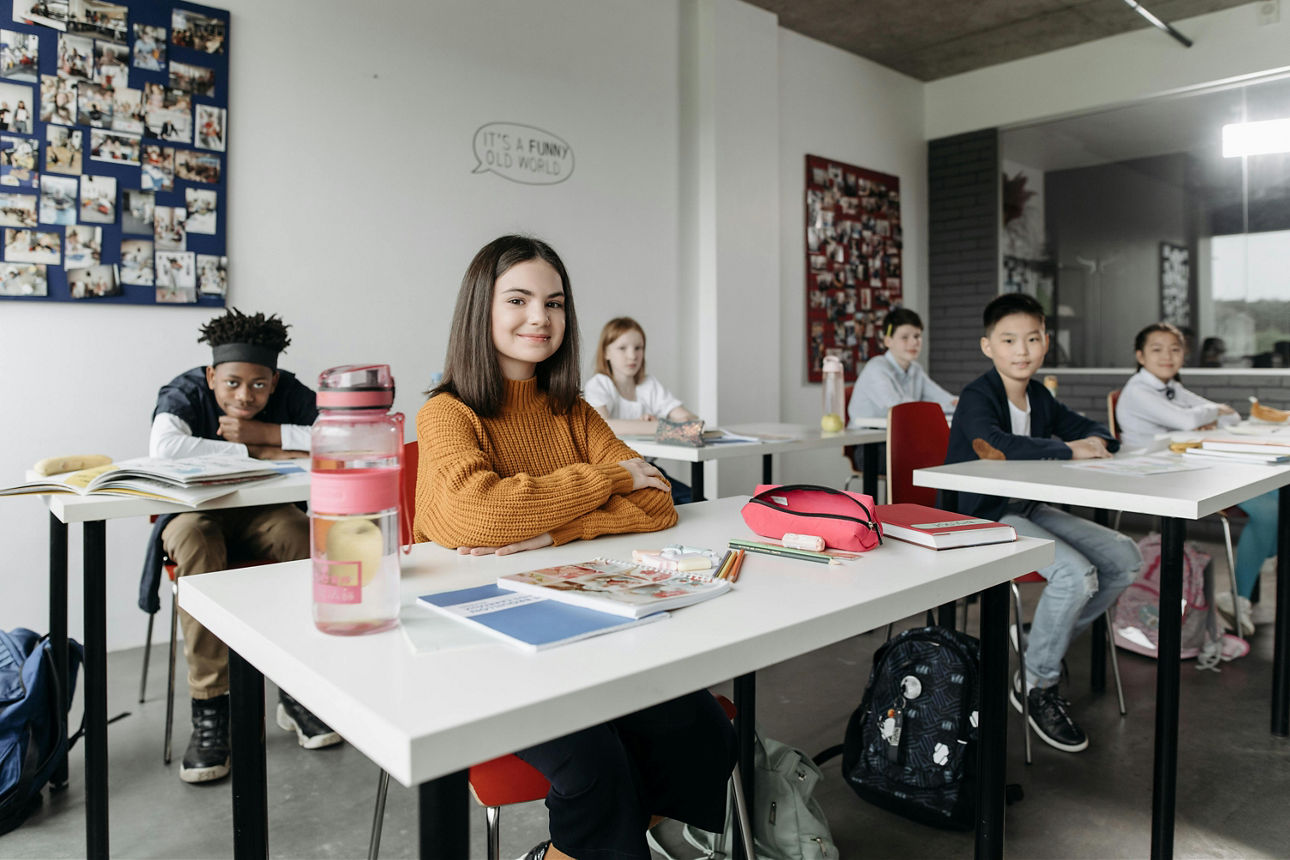 Vier Kinder sitzen in der Klasse und lächeln in die Kamera