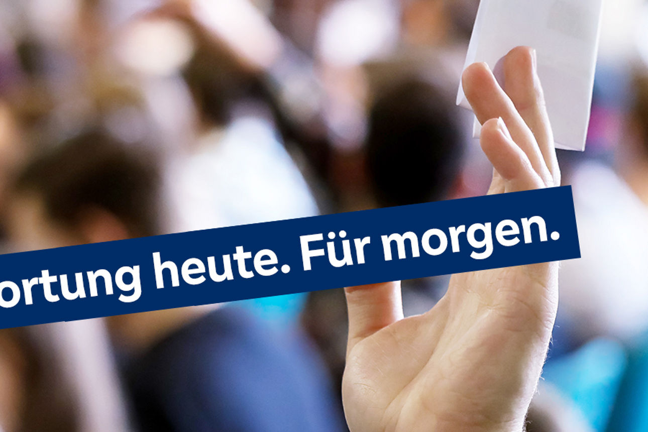Hand mit Stimmkarte vor Publikum und Slogan "Verantwortung heute. Für morgen."