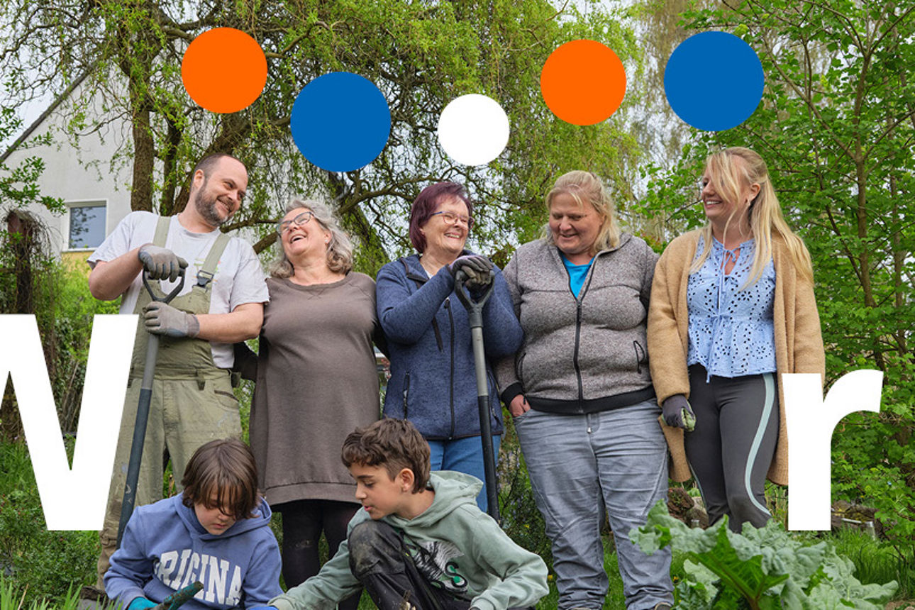 Glückliche Menschen aus verschiedenen Generationen stehen gemeinsam in einem Schrebergarten