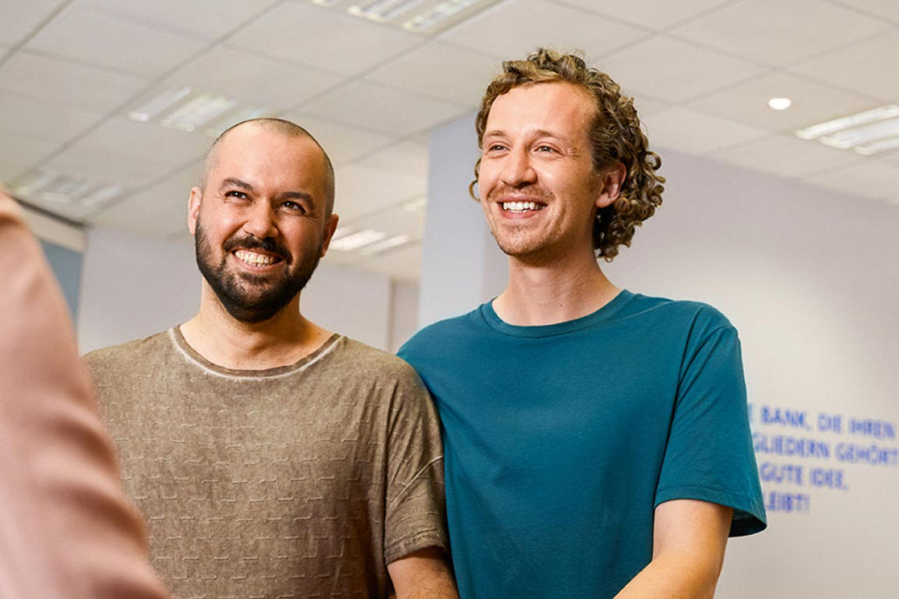 Zwei Männer bei Ihrer Bankberaterin, die sich über Ihr wachsenes Vermögen freuen