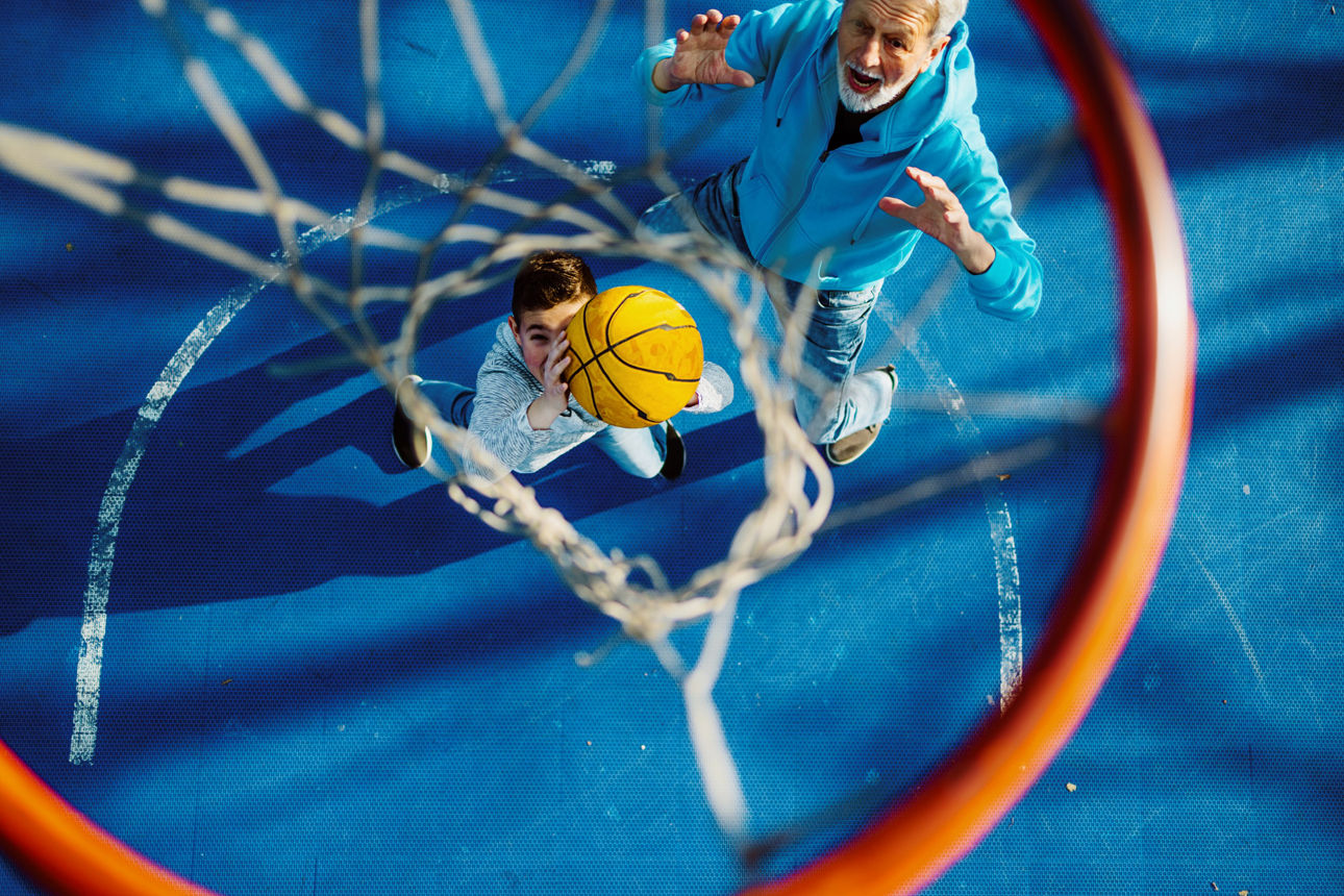Personen werfen einen Basketball in einen Basketballkorb