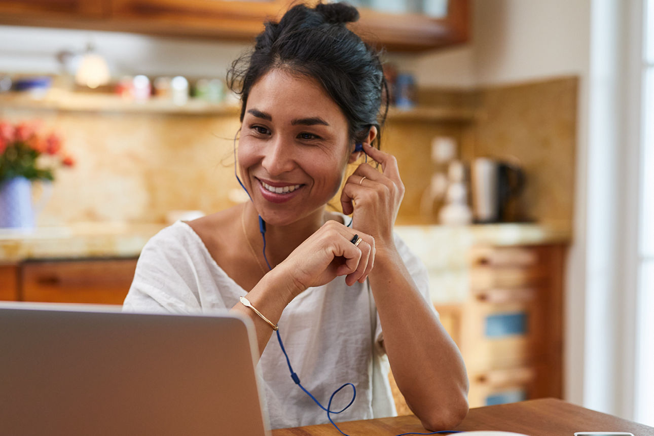 Eine Frau arbeitet in der Küche an einem Notebook