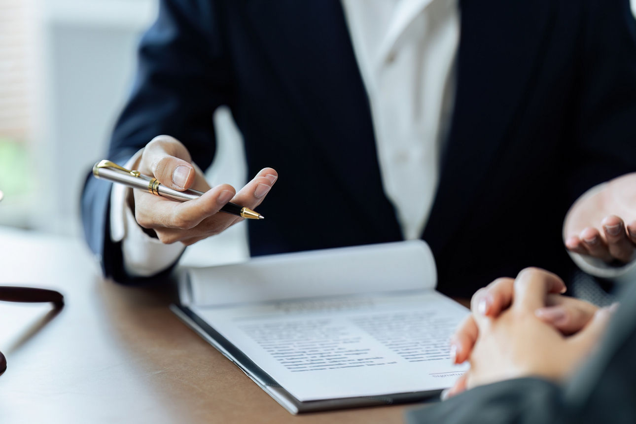 Hände und Schreibtisch eines Anwaltes im Gespräch mit Klienten