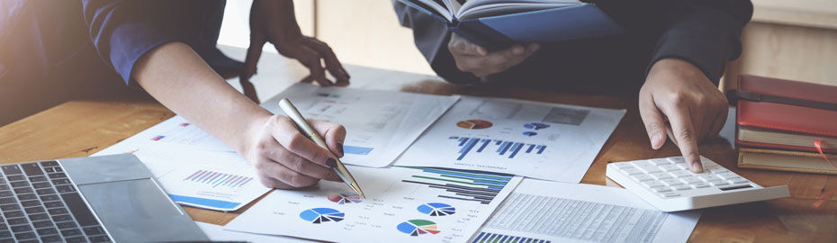 Zwei Personen analysieren Finanzdaten mit Diagrammen, Taschenrechner und Laptop – Symbol für professionelle Vermögensplanung 