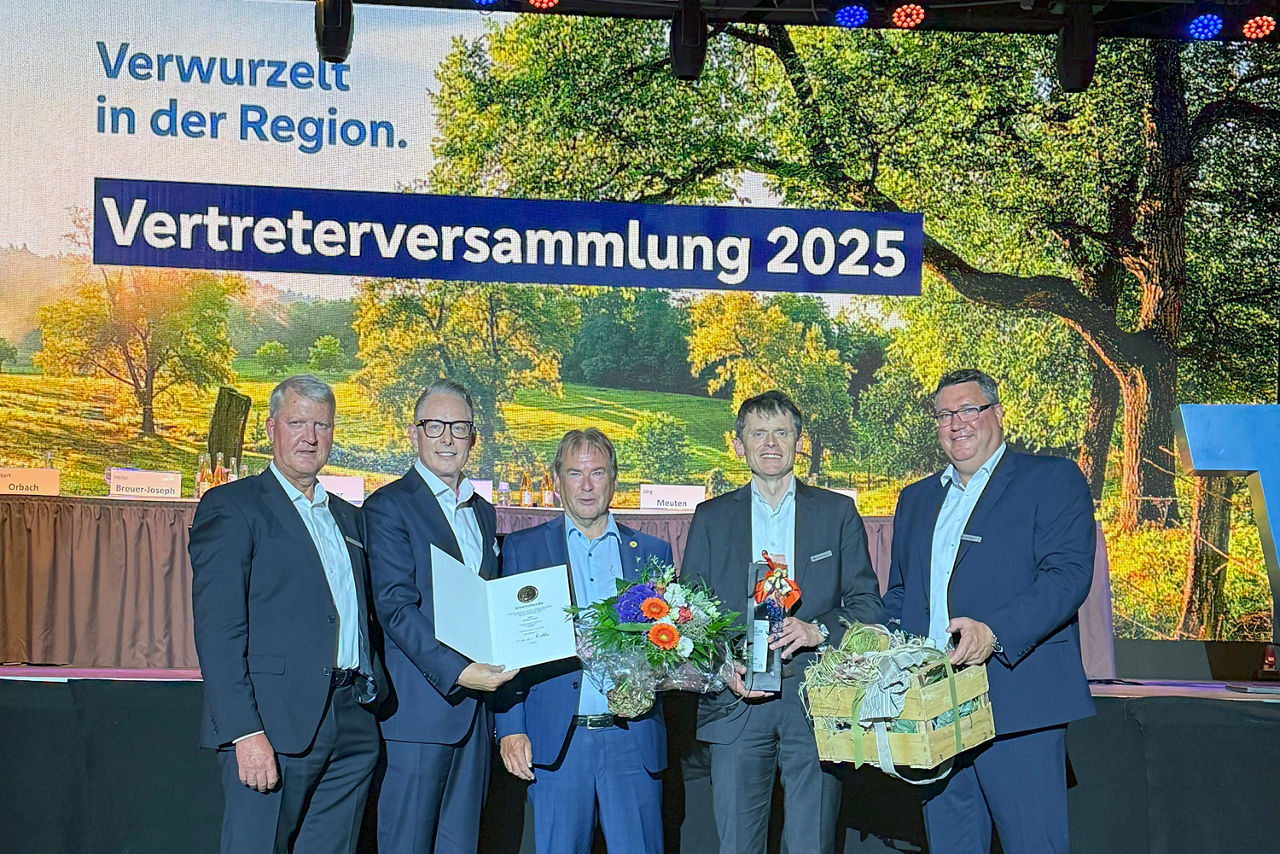 Helmut Vilmar (Vorstand), Tobias Jasper (Bankenbetreuuer Genoverband e. V.), Norbert Orbach, Christoph Gubert (Vorstand), Jörg Meuten (Aufsichtsratsvorsitzender) stehen vor einer Leinwand