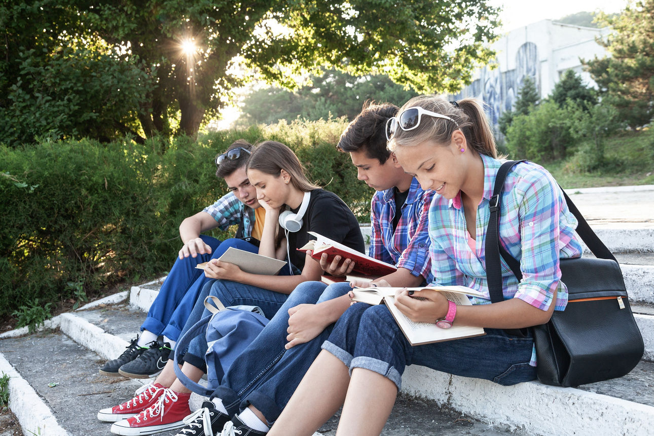 Eine Gruppe Jugendliche die auf einer Treppe sitzen und lesen