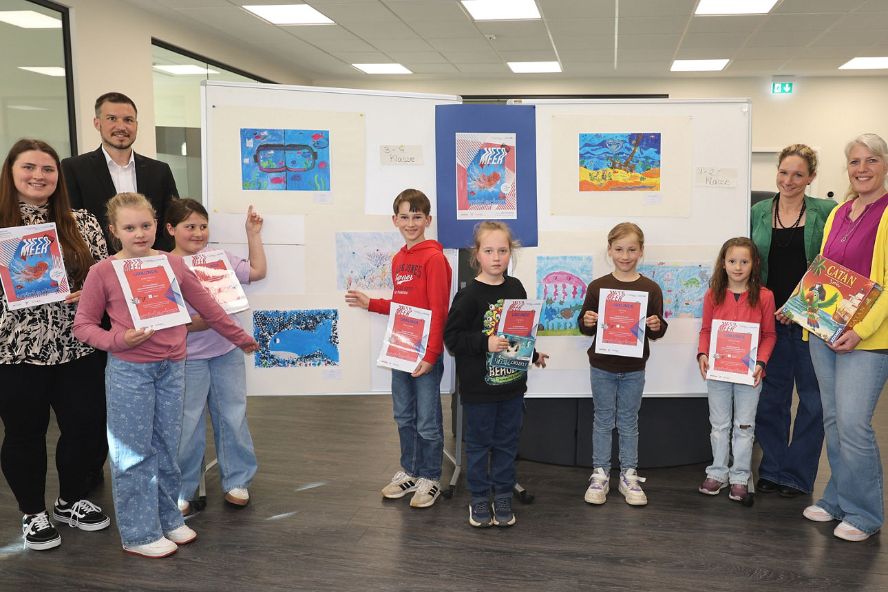 Kinder präsentieren stolz ihre Kunstwerke, begleitet von Erwachsenen im Ausstellungsraum.