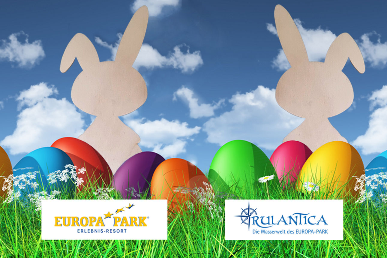 Drei Holz-Osterhasen sitzen in einer Wieser mit bunten Eiern