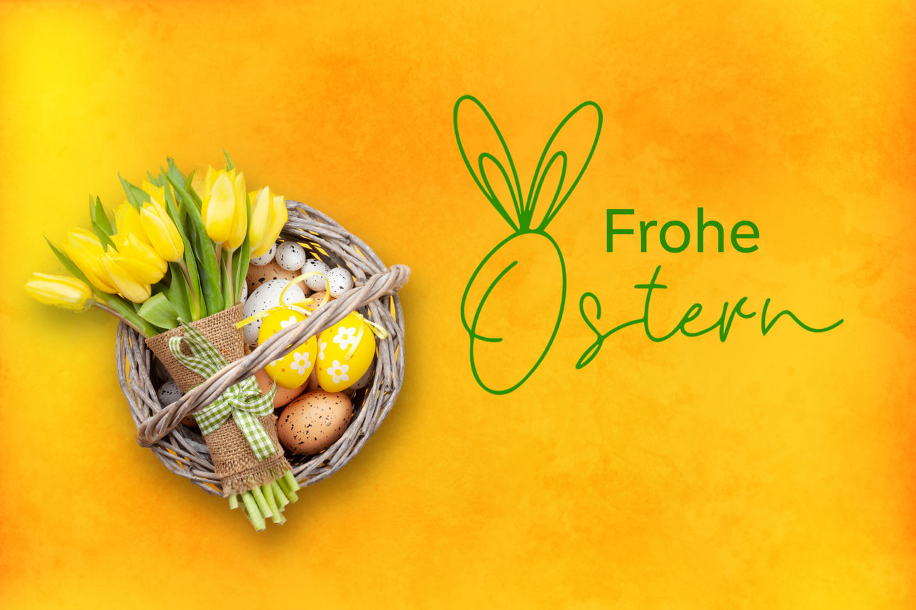 Ein Osterkorb mit bunten Eiern und gelben Tulpen.