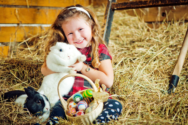 Cute little girl with two bunnies and Easter eggs