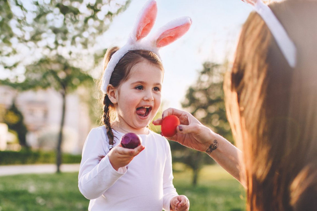 Mädchen mit Hasenohren hält ein Osterei in der Hand
