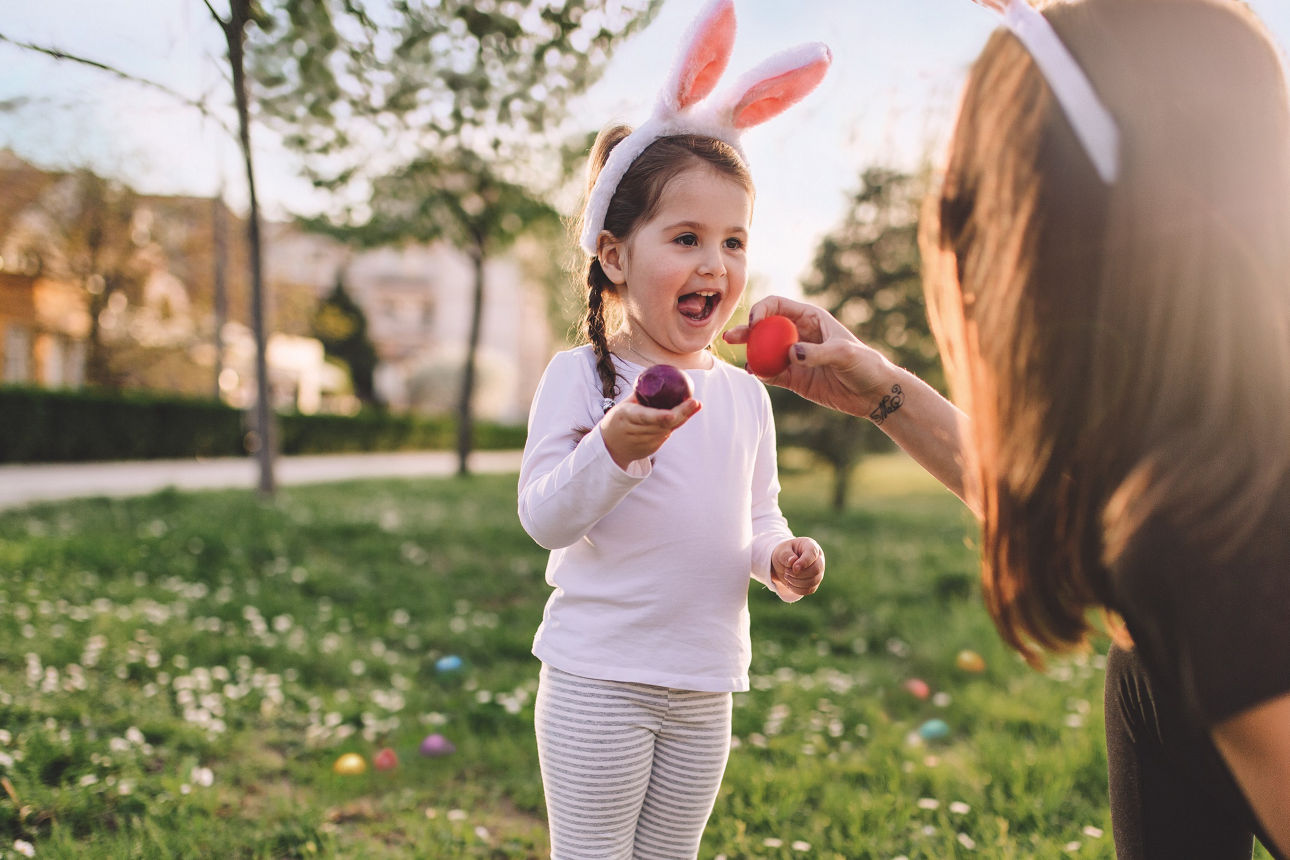 Mutter sucht mit Kind Ostereier im Garten