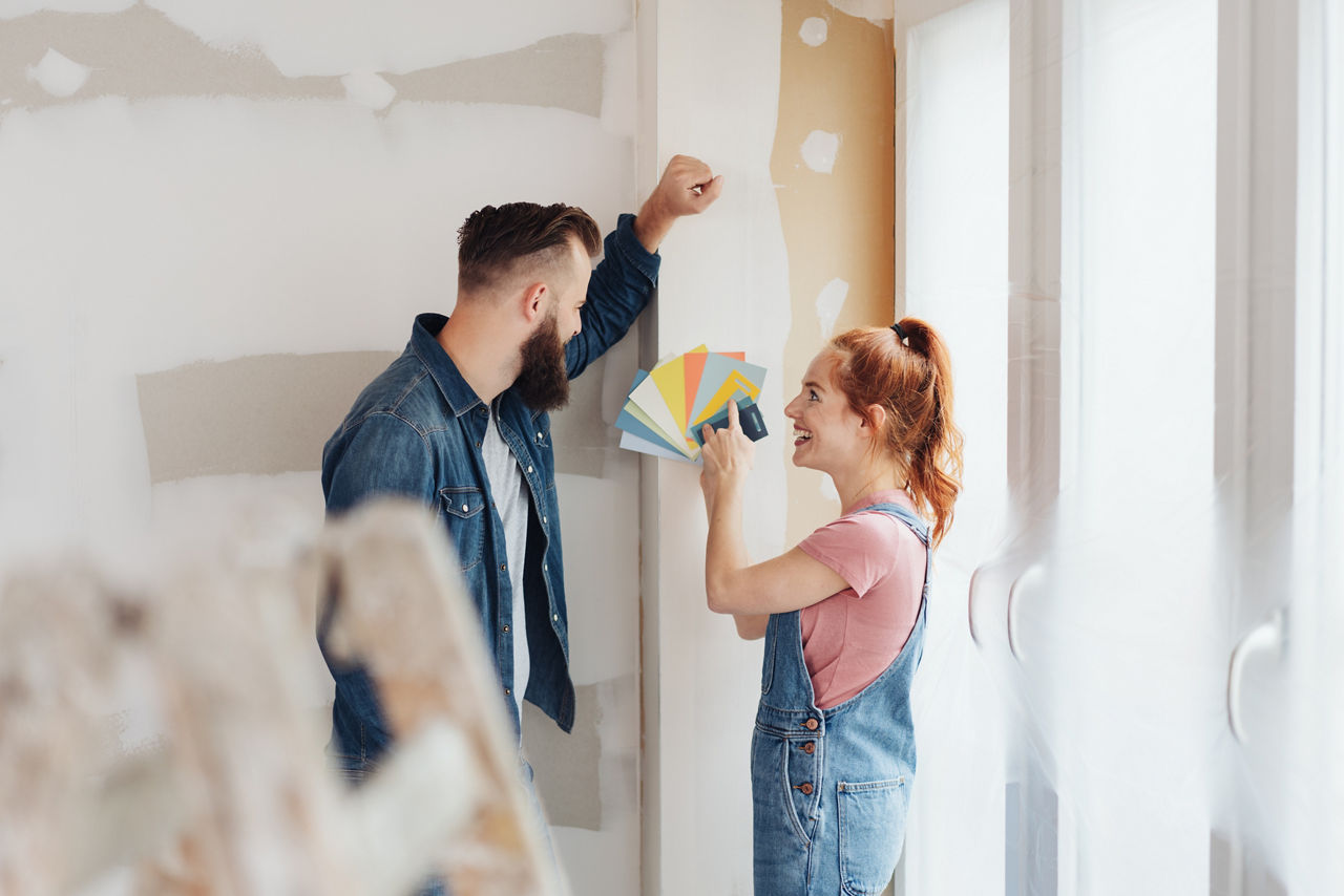 Mann und Frau, junges Pärchen sind mitten bei der Renovierung uns suchen Farben für die Wand aus