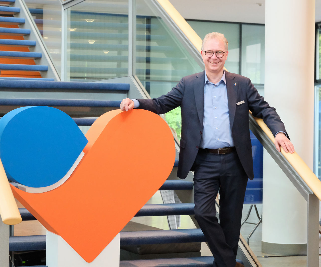 Vorstandsvorsitzender Jürgen Pütz steht neben einer Skulptur des Volksbank-Herzens