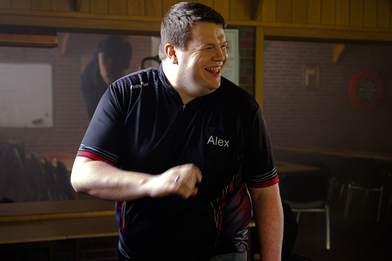 Alex lachend beim Dart spielen