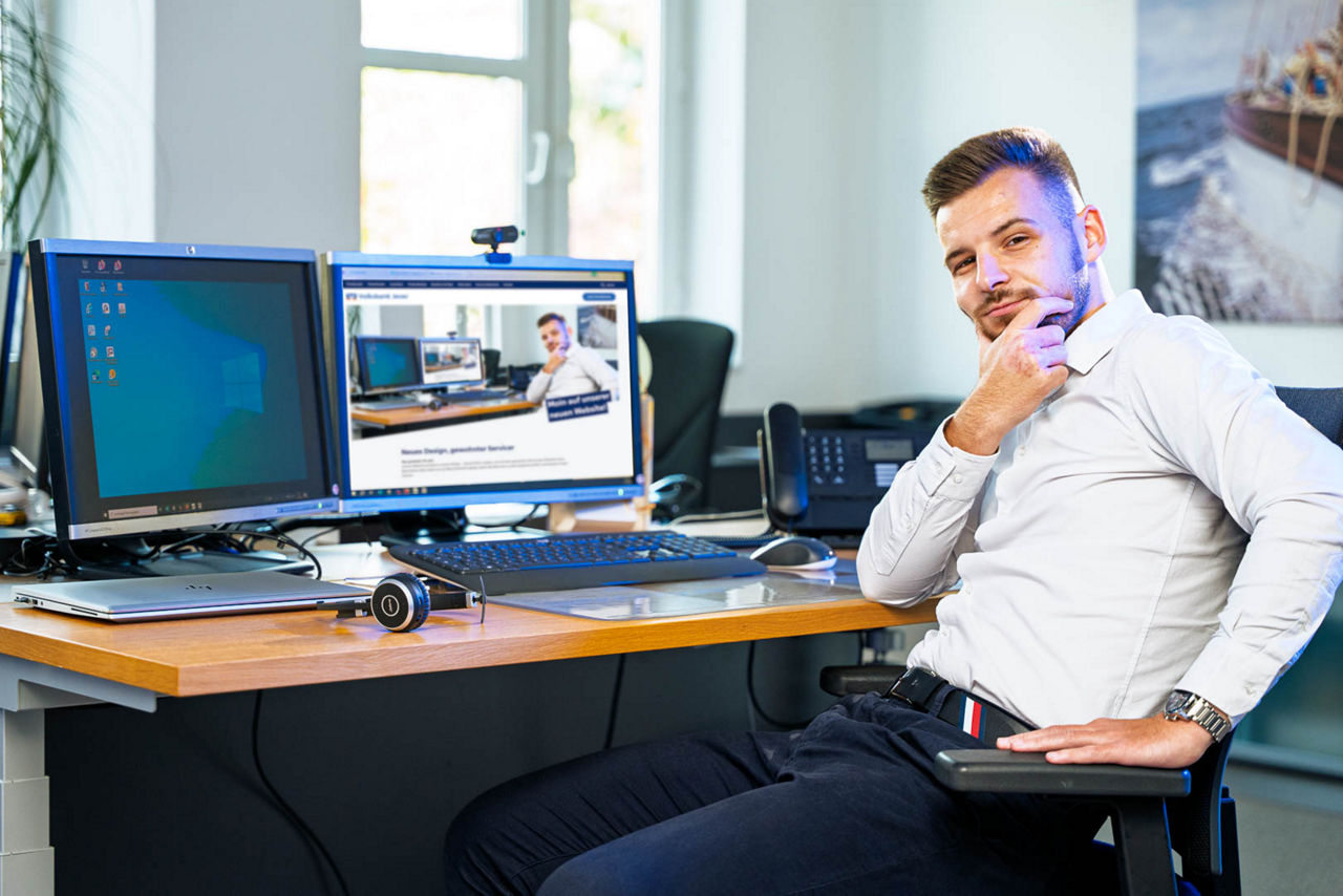 Mann sitzt am PC und lächelt in die Kamera