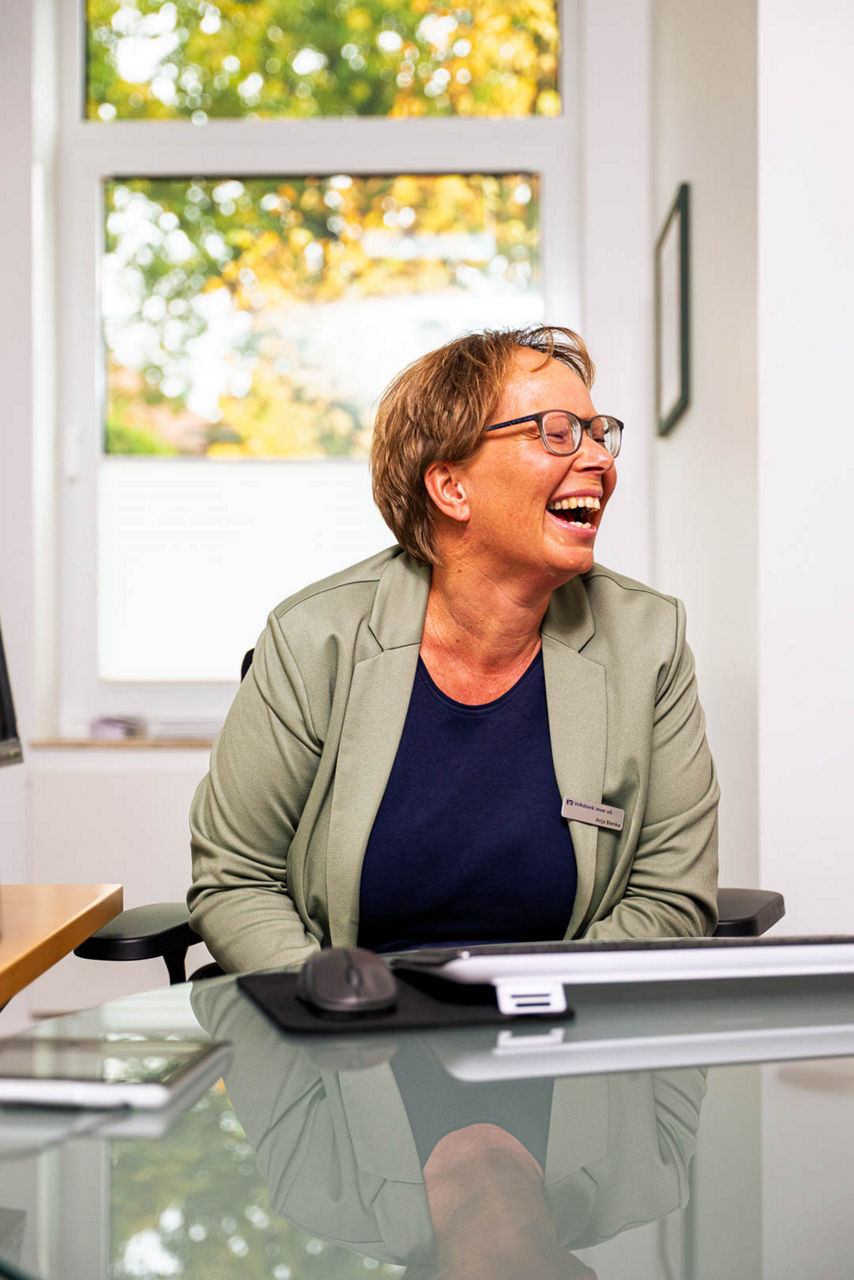 Eine Frau sitzt lächelnd am Schreibtisch in einer Bank