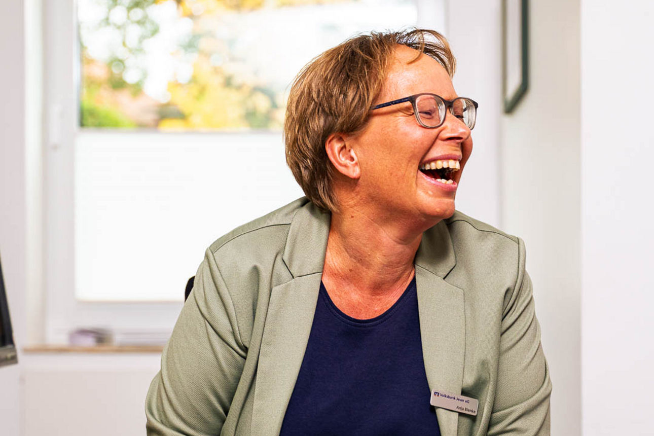 Eine Frau sitzt lächelnd am Schreibtisch in einer Bank