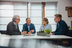 Vier Mitarbeitende sitzen an einem Tisch und besprechen sich